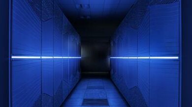 Two supercomputer racks illuminated in blue light.