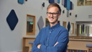 A smiling man with arms folded standing in the Hartree Centre foyer.