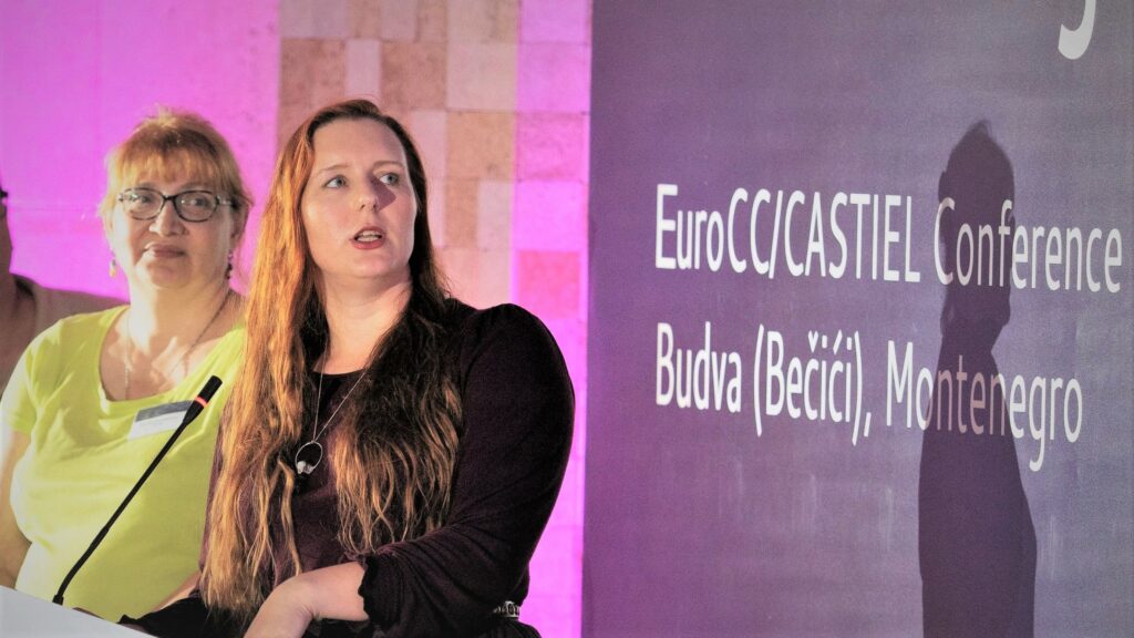 Two people stood at a lectern presenting at a conference.