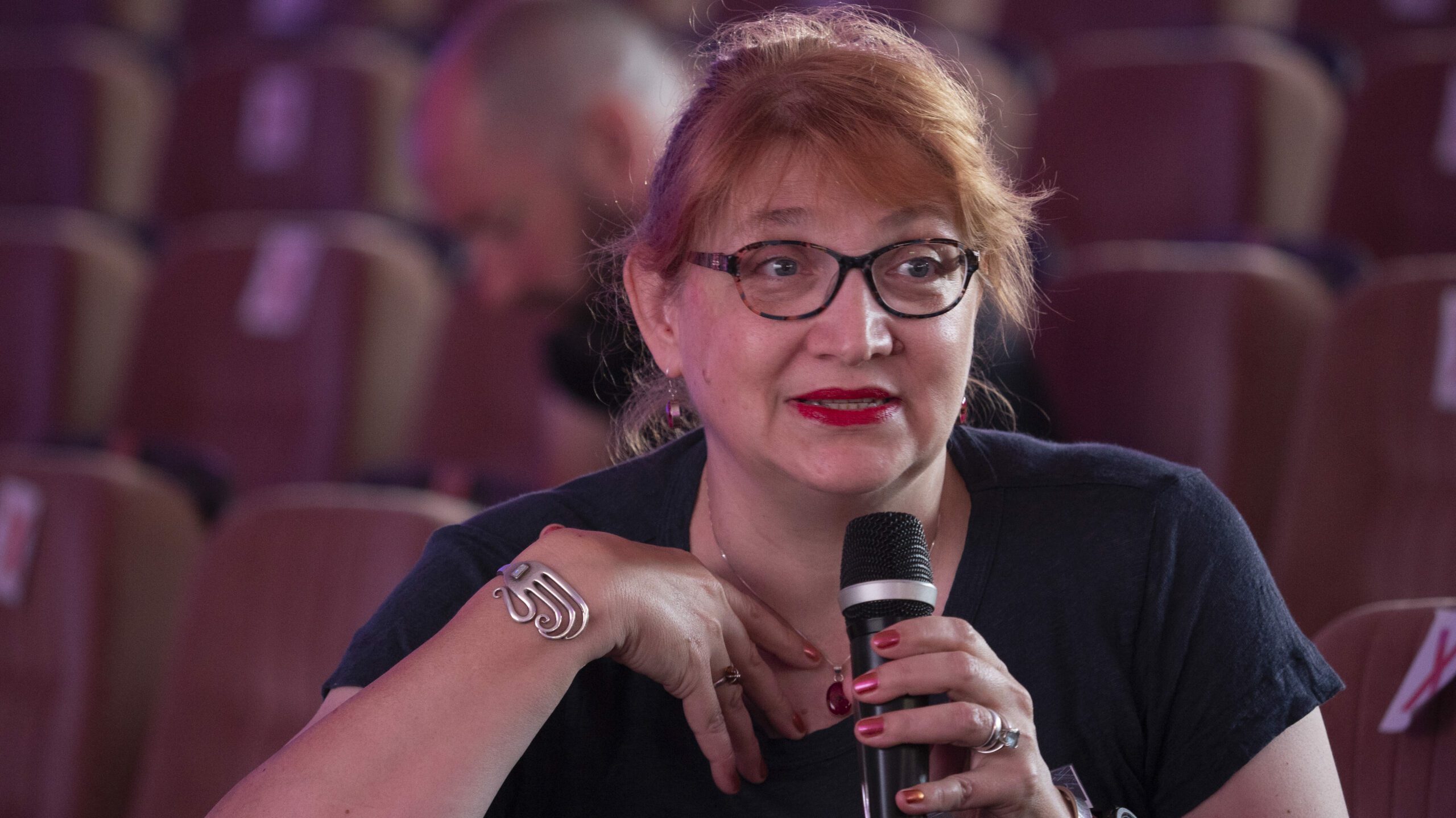 A woman at a conference speaking into a microphone.