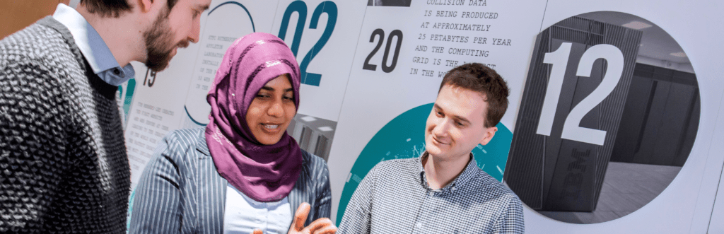 Two men and one woman discussing ideas in an office corridor