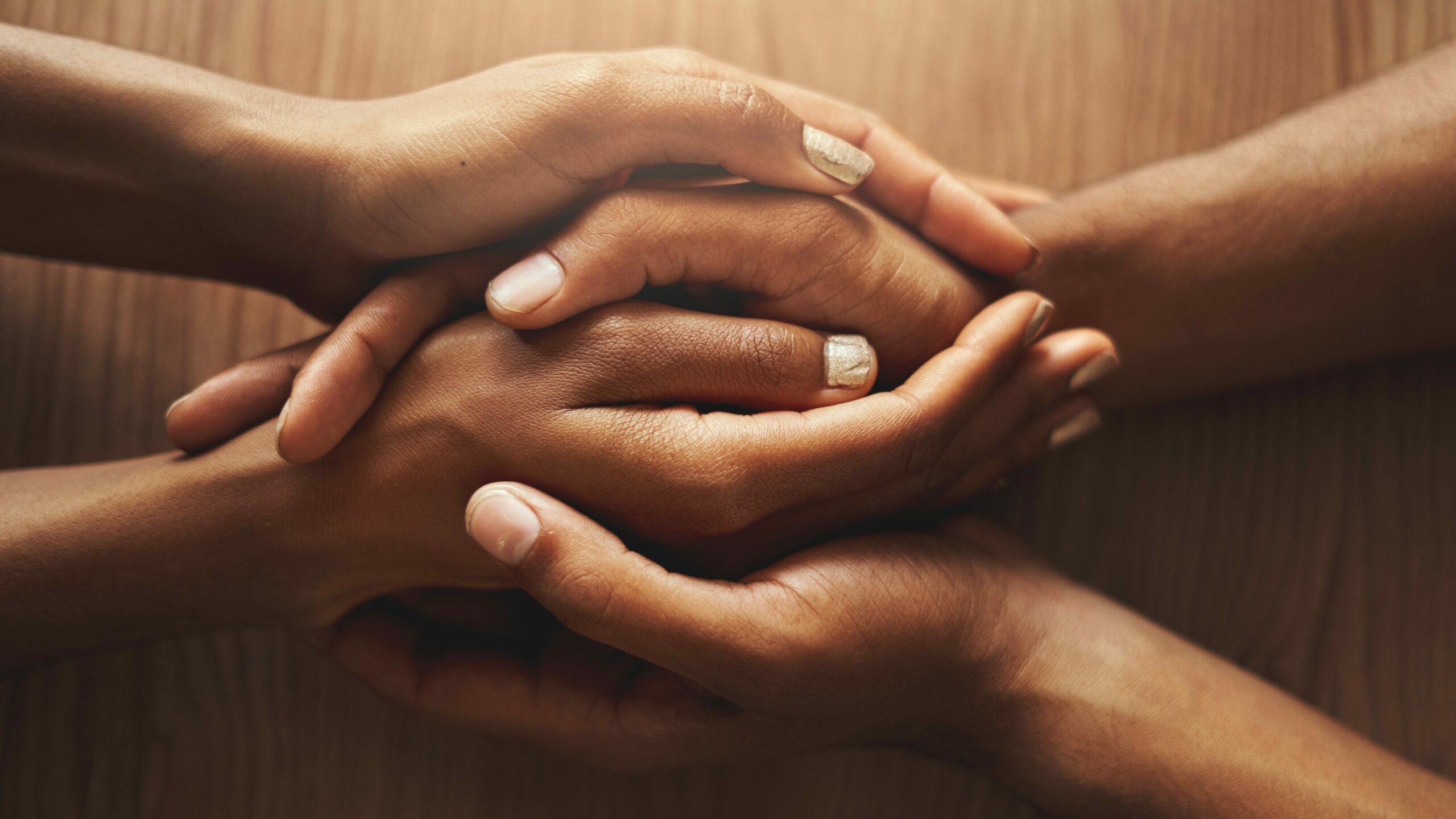 An overhead view of couple holding their hands on wooden desk