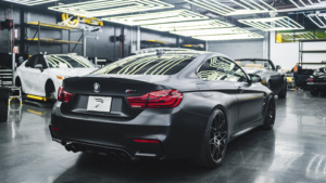 A black car on a factory floor.