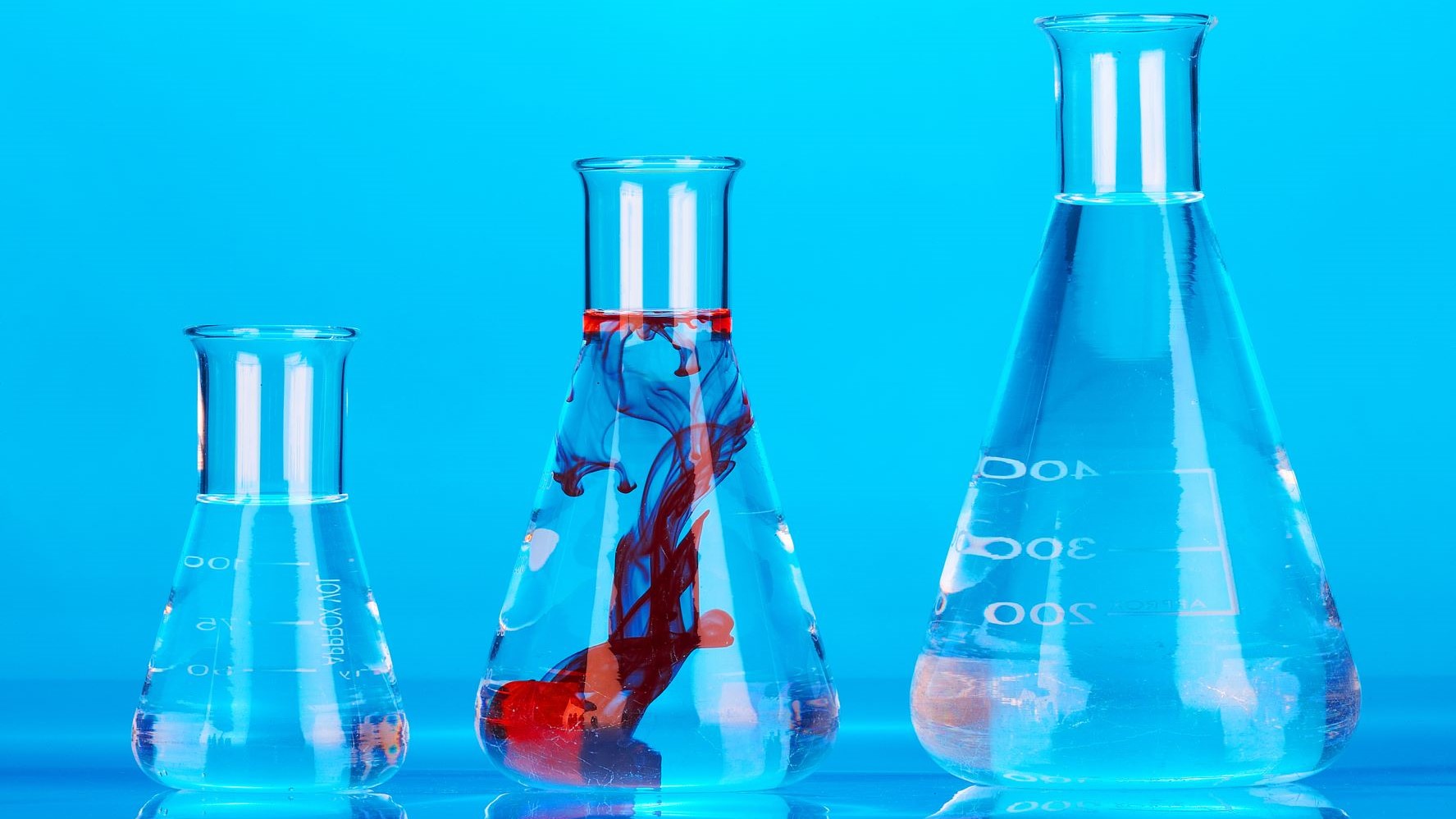 Three chemistry beakers filled with blue and red liquids.