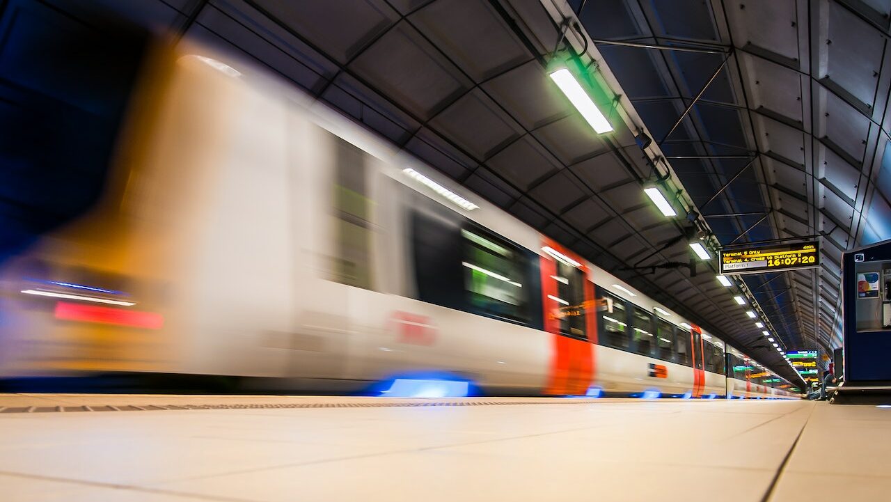 A train with motion blur is passing through a station plaform.