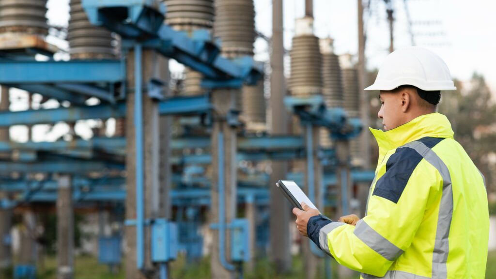 Electrical worker engineer working with digital tablet near tower with electricity.
